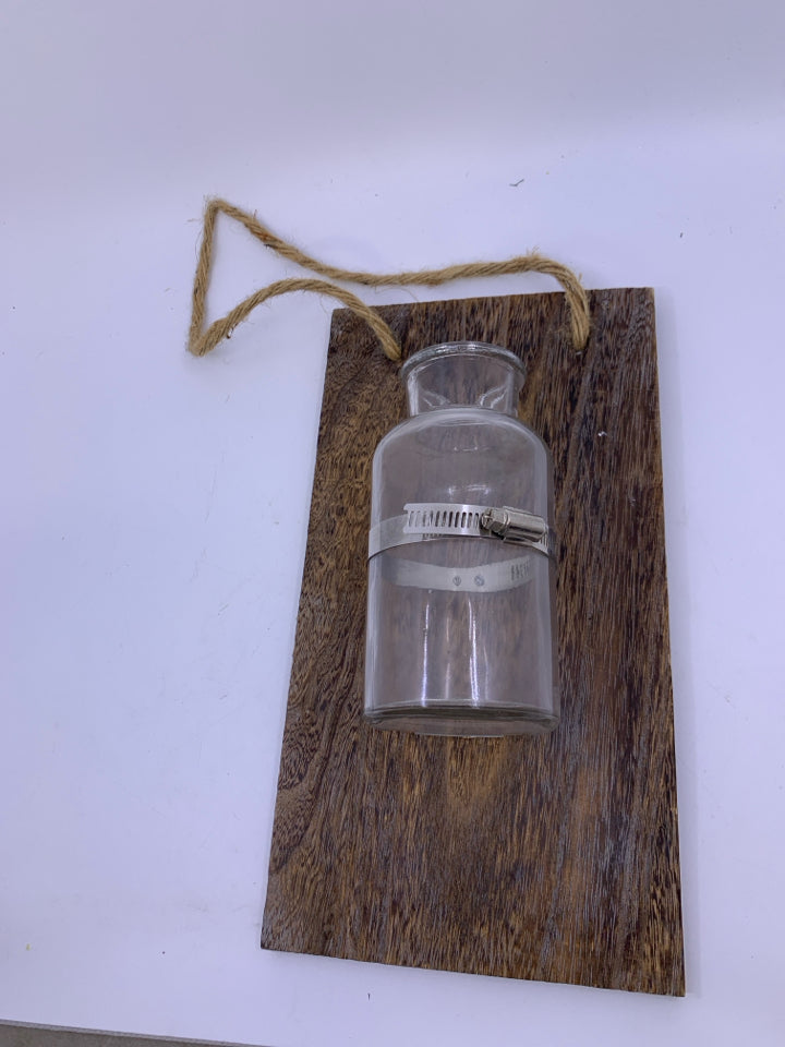 GLASS BOTTLE VASE ON PLANK.