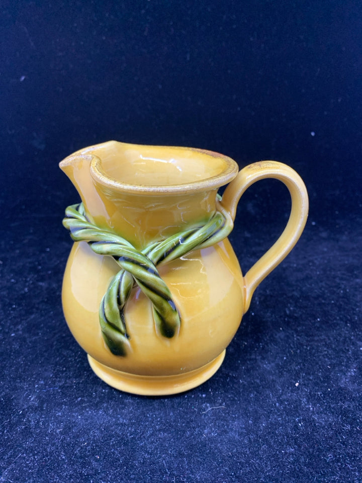 YELLOW POTTERY CREAMER W/ GREEN ROPE DETAIL.