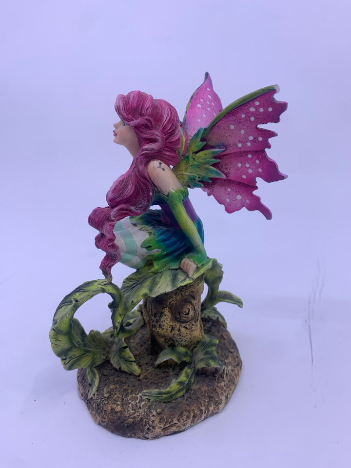 RESIN FAIRY SITTING ON A STUMP W/ PURPLE WINGS.