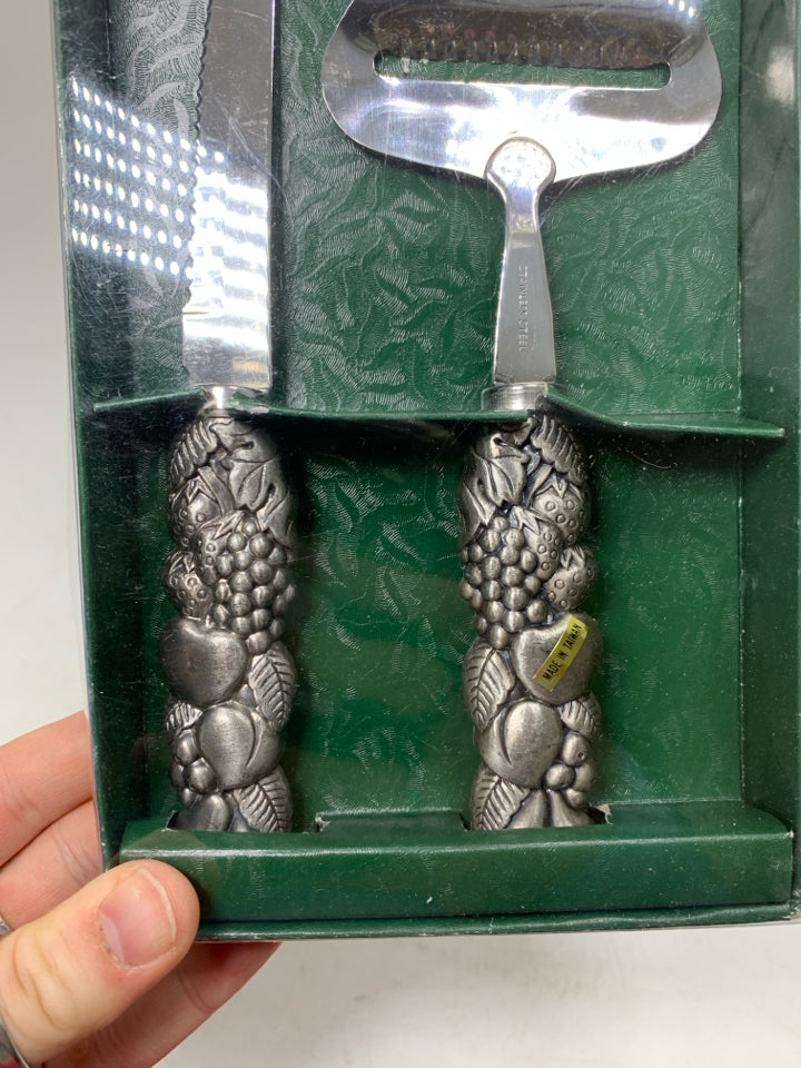NIP 2 CHEESE KNIFES W/ FRUIT EMBOSSED HANDLES.