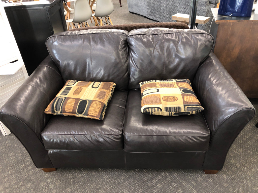 BROWN LEATHER LOVE SEAT W/2 GEOMETRIC STYLE PILLOWS.
