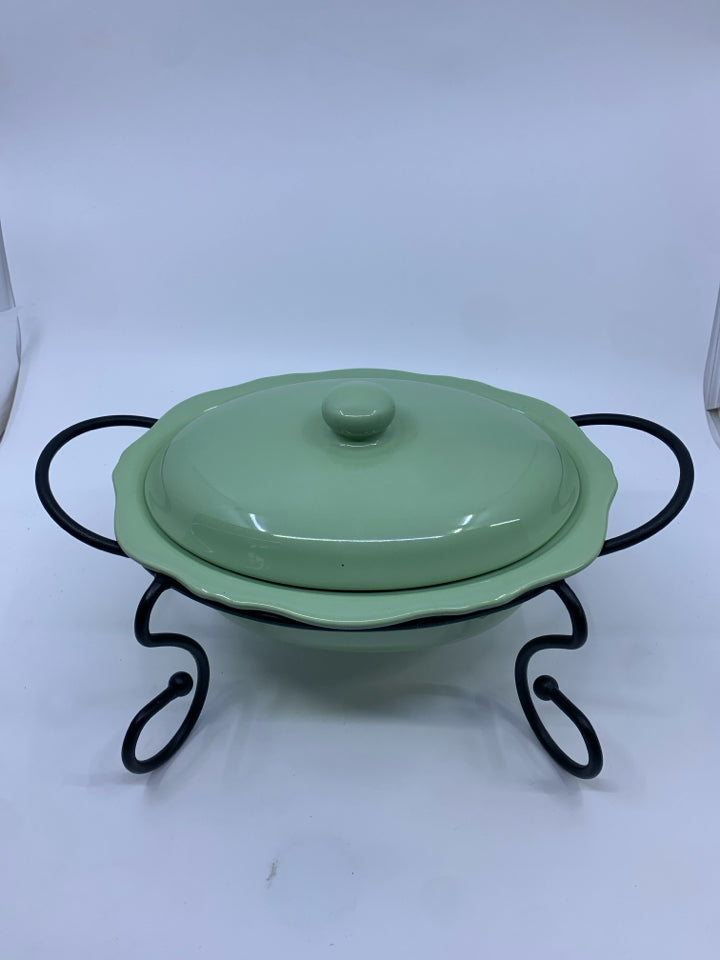 GREEN CASSEROLE DISH W LID AND BLACK METAL STAND.