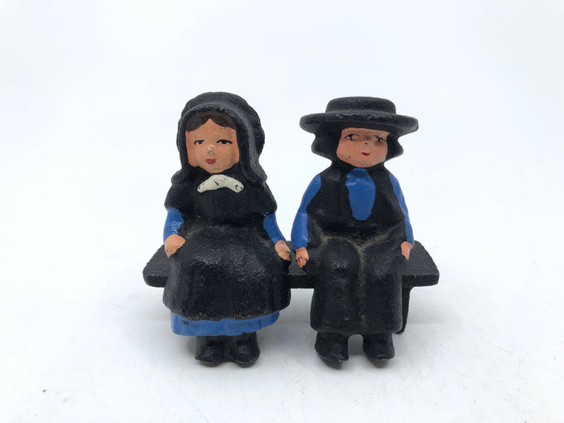 3PC CAST IRON AMISH COUPLE SITTING ON BENCH.