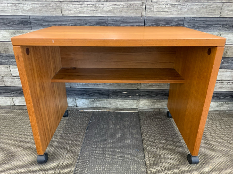 SMALL HEAVY WOOD DESK ON WHEELS W/ INSIDE SHELF.