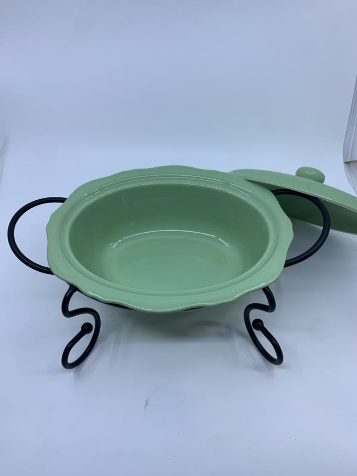 GREEN CASSEROLE DISH W LID AND BLACK METAL STAND.