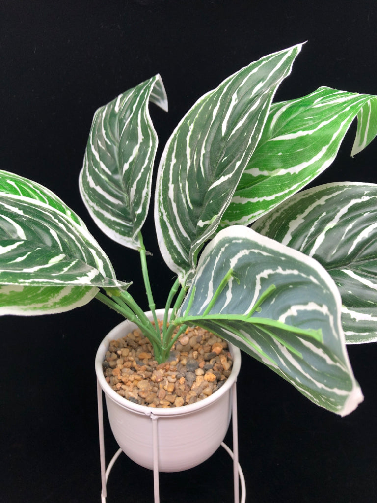 FAUX GREEN PLANT IN WHITE RAISED METAL PLANTER.