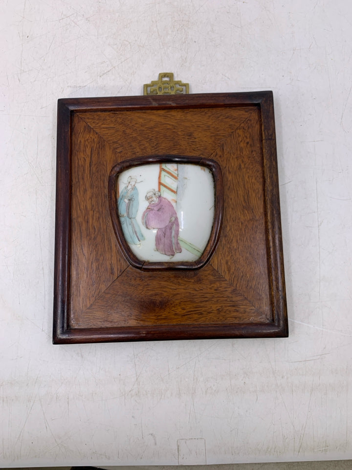 WOOD WALL HANGING W/ 2 MEN LOOKING AT EACHOTHER POTTERY PIECE.