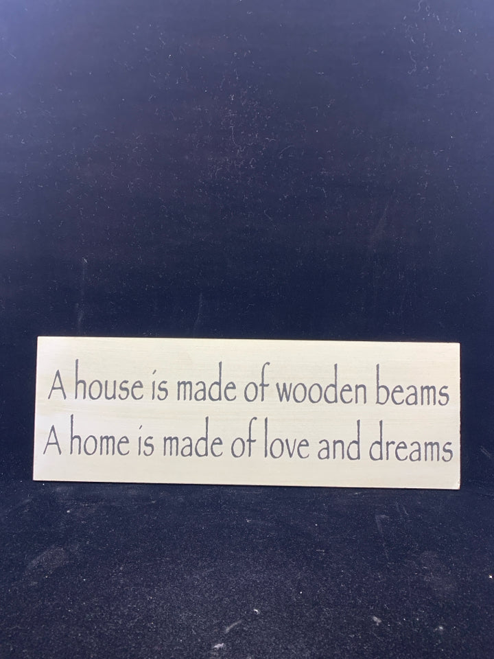 A HOUSE IS WHITE WOOD WALL ART W/ BLACK LETTERS.