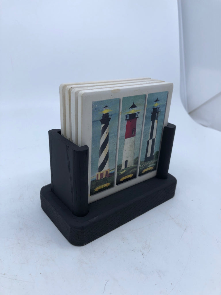 4 LIGHT HOUSE COASTERS IN BLACK WOOD STAND.