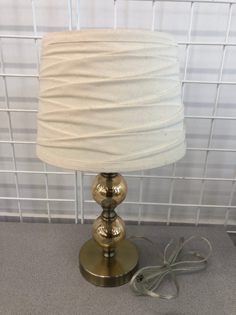 GOLD CLEAR GLASS LAMP W/FOLDED CREAM SHADE.