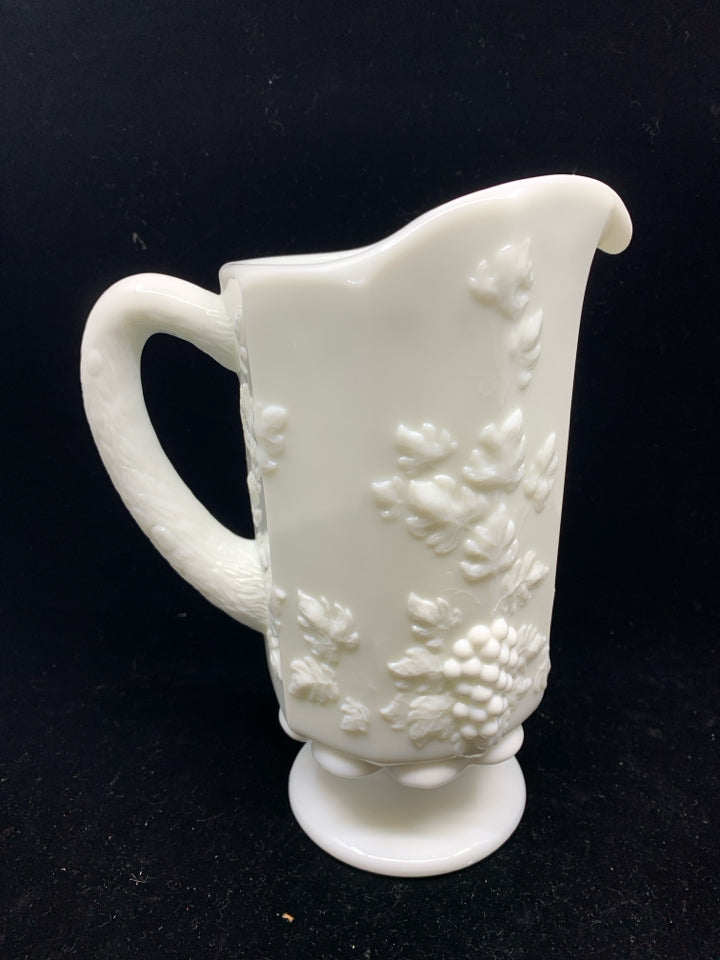 VTG MILK GLASS FOOTED PITCHER W/ EMBOSSED GRAPES + VINES.