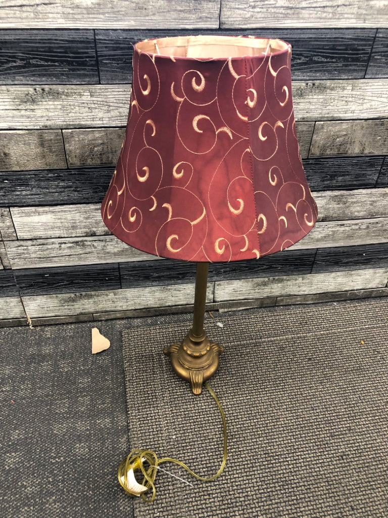 GOLD COLORED METAL DISTRESSED LAMP W/ RED SCROLL SHADE.