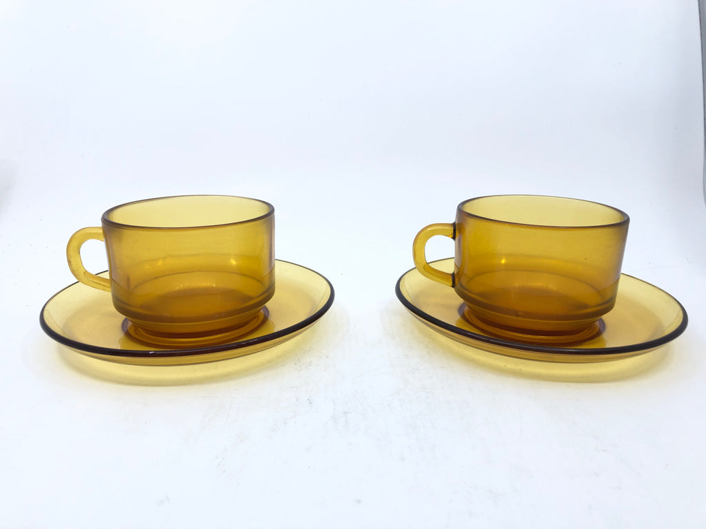 2 AMBER GLASS MUGS AND SAUCERS.