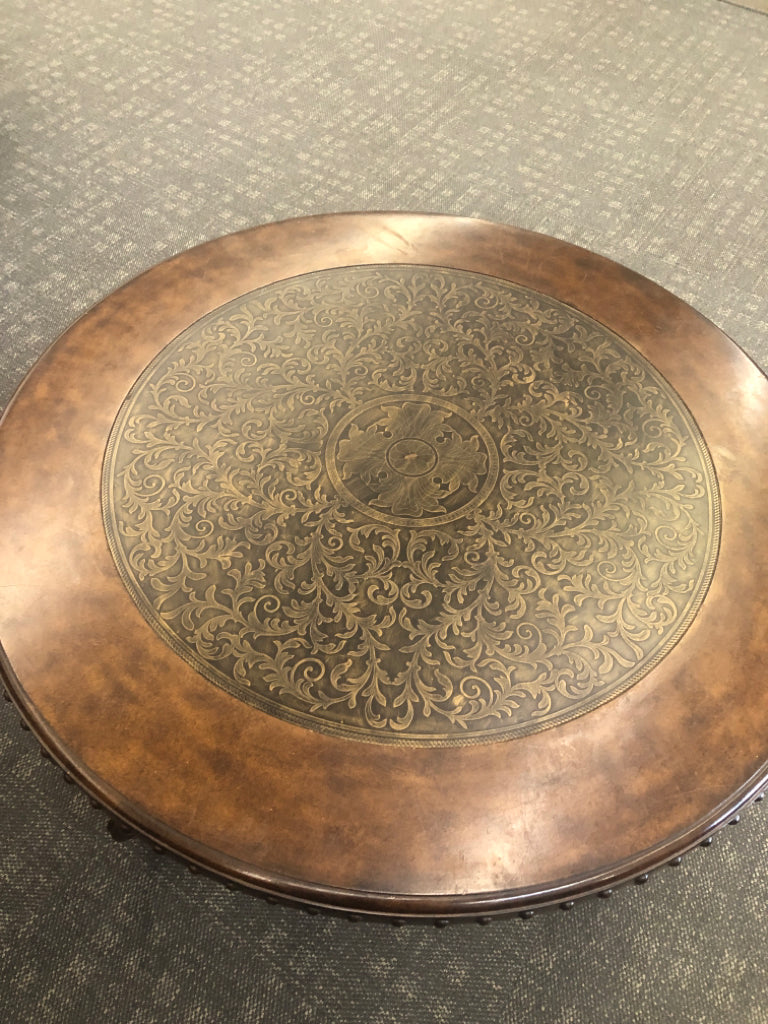 ORNATE BROWN COFFEE TABLE W/CENTER DESIGN & METAL ACCENTS.