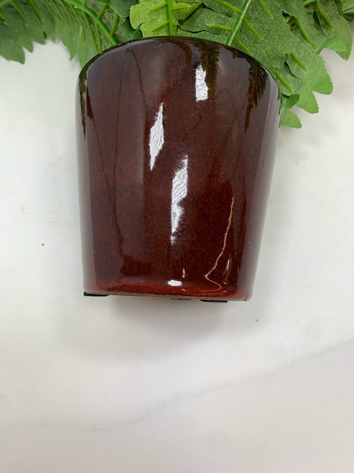 FAUX FERN IN BROWN CERAMIC POT.