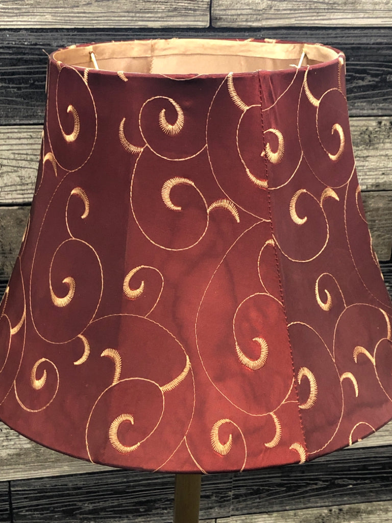 GOLD COLORED METAL DISTRESSED LAMP W/ RED SCROLL SHADE.