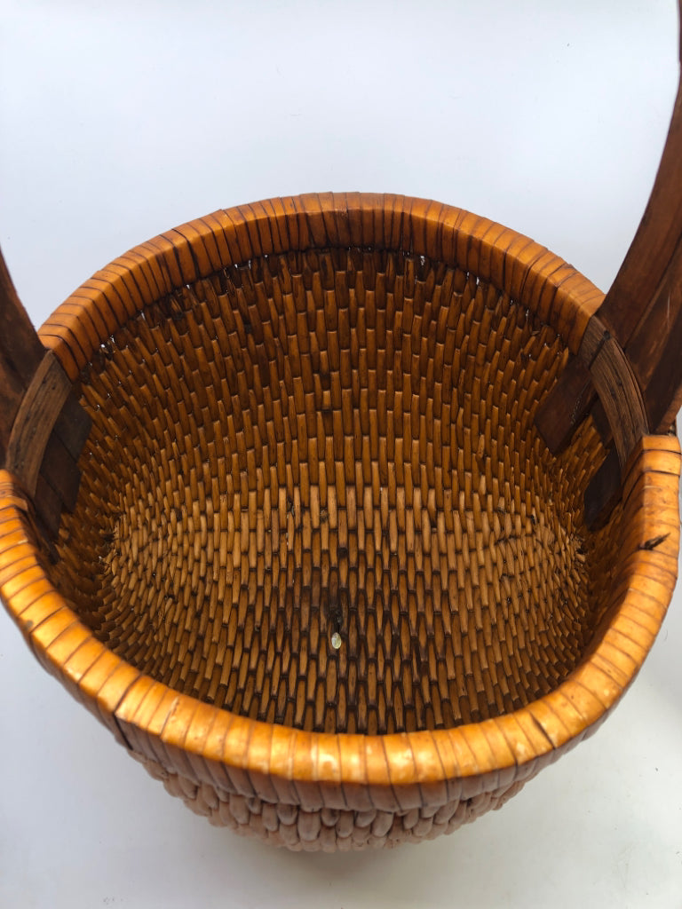 SMALL ROUND ORANGE TIGHT WEAVE BASKET W/ 3 CROSSED HANDLE.