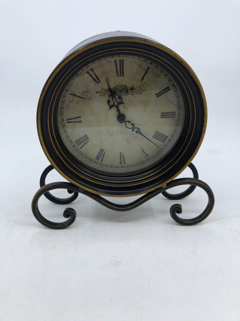 METAL BLACK SCROLL FOOTED CLOCK W/ GOLD DETAILS.