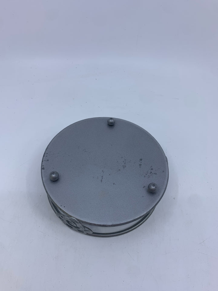 LARGE CANDLE IN METAL HOLDER.