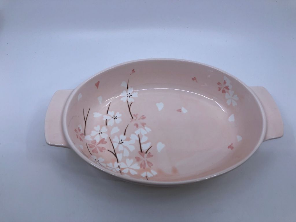 LIGHT PINK OVAL BAKING DISH W WHITE FLORAL AND HANDLES.