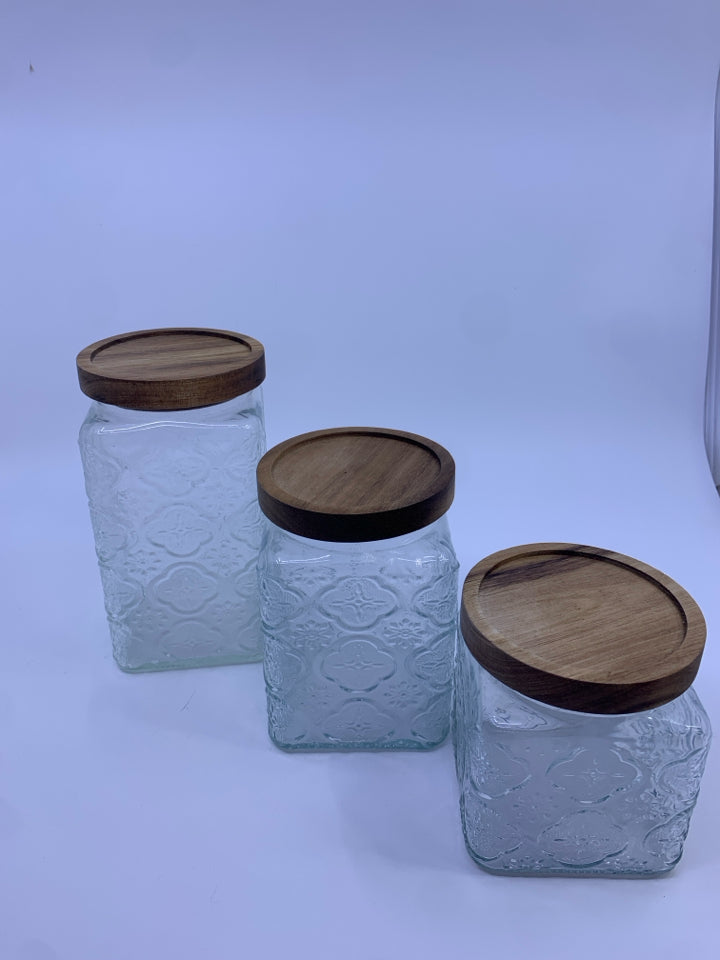3 EMBOSSED CANISTERS W WOOD TOPS.