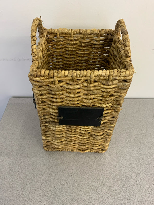 TALL WOVEN BASKET WITH CHALK BOARD LABELS AND HANDLES.