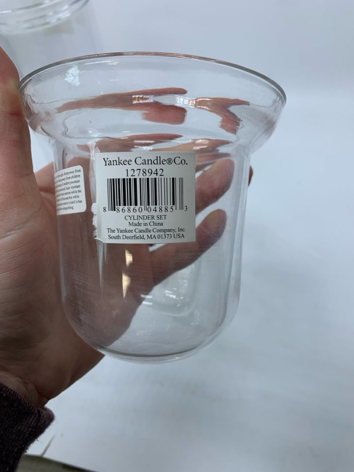 2 CLEAR GLASS CYLINDERS W/ DROP IN TEA LIGHTS.