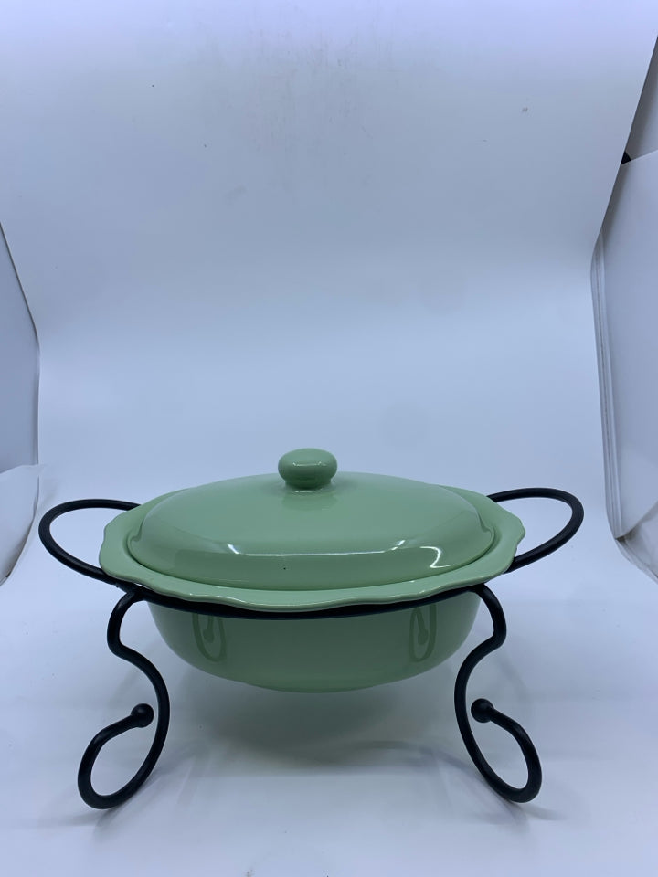 GREEN CASSEROLE DISH W LID AND BLACK METAL STAND.