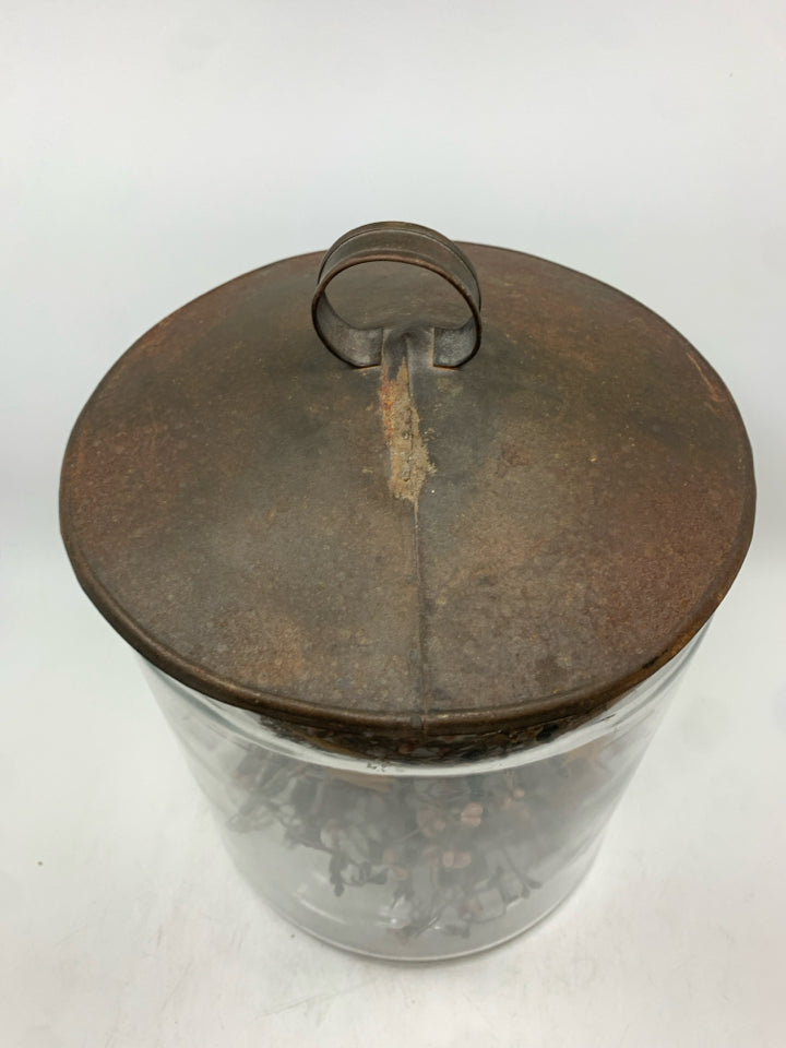 PRIMITIVE GARLAND IN METAL COVERED GLASS CANISTER.
