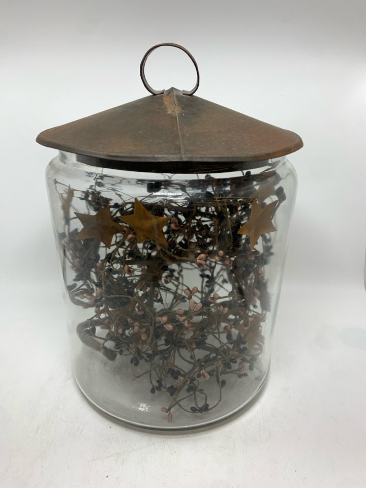 PRIMITIVE GARLAND IN METAL COVERED GLASS CANISTER.