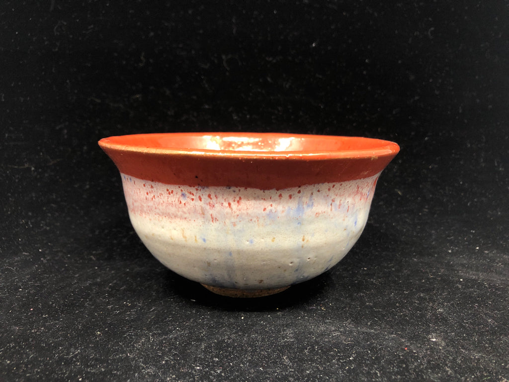 ORANGE POTTERY BOWL W LIGHT OUTSIDE.