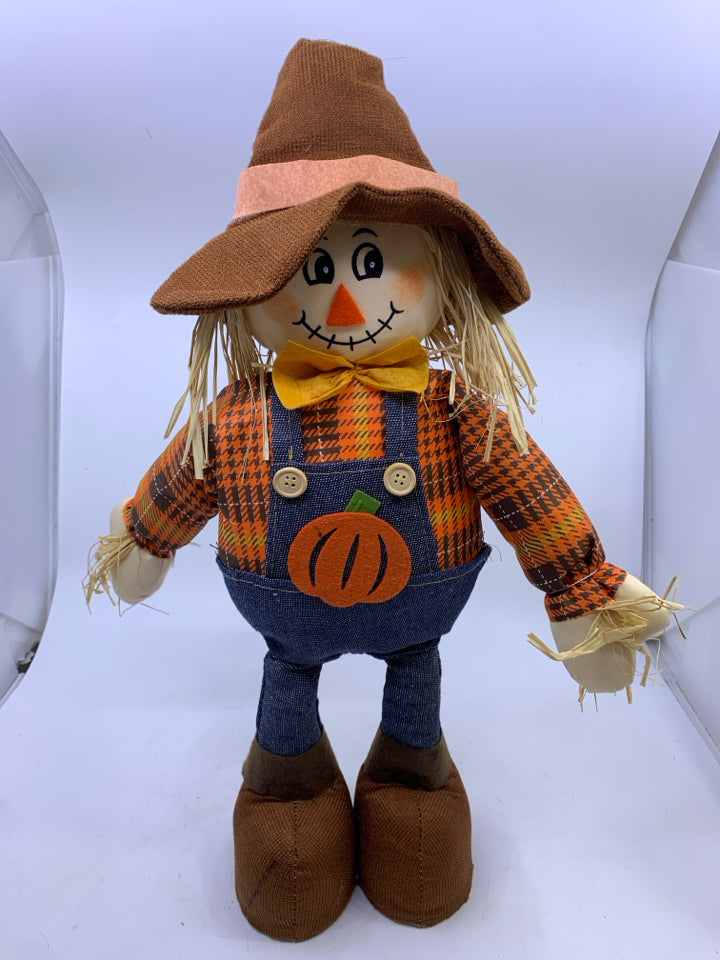 STANDING SCARECROW IN ORANGE SHIRT JEANS OVERALLS.