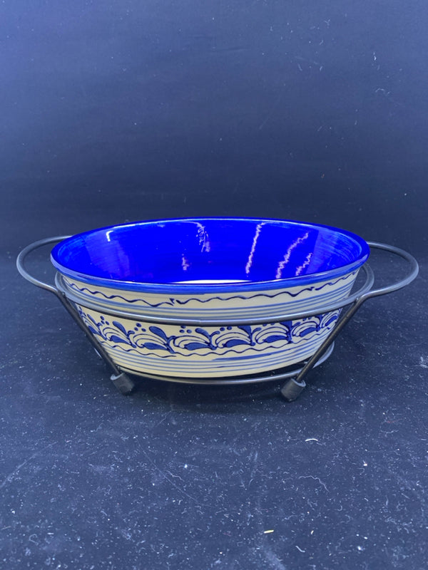 BLUE AND WHITE OVAL DISH IN BLACK METAL STAND.