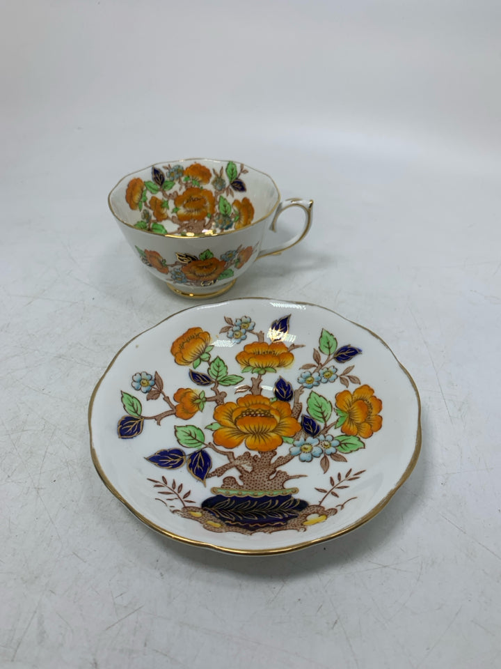 ORANGE FLOWERS IN PLANTER W/ GOLD RIM.