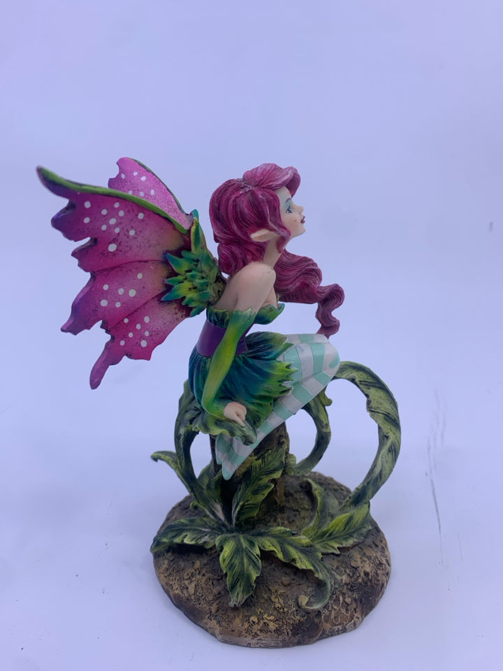 RESIN FAIRY SITTING ON A STUMP W/ PURPLE WINGS.
