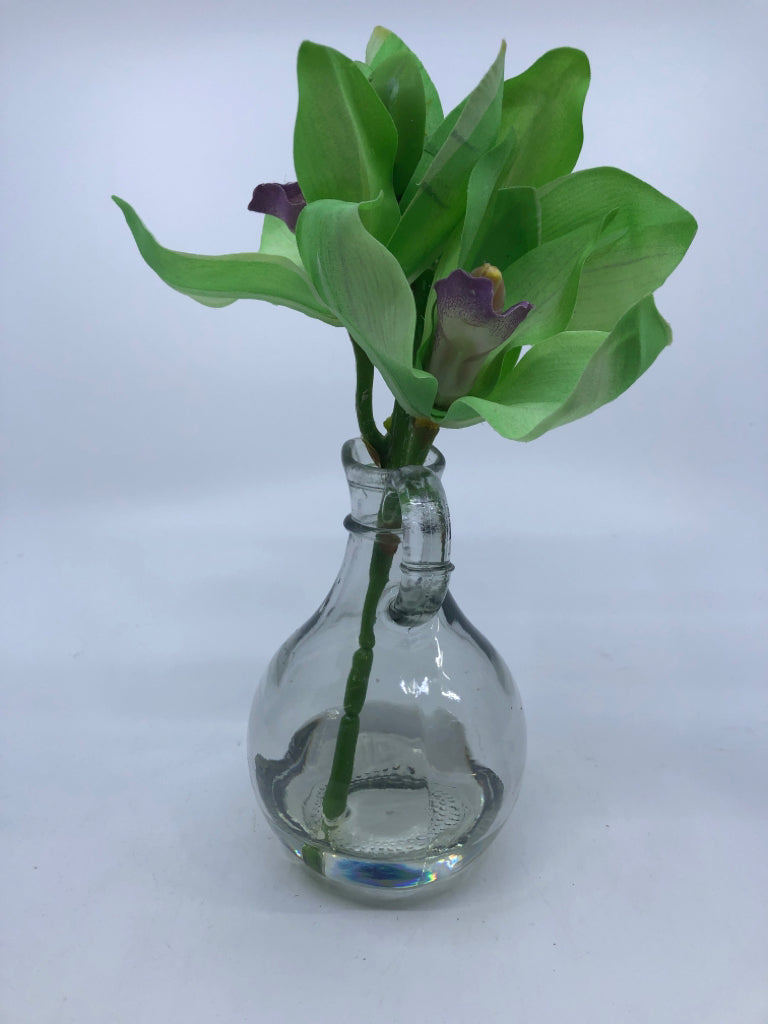 GLASS PITCHER VASE W/GREENS AND PURPLE FLOWERS.