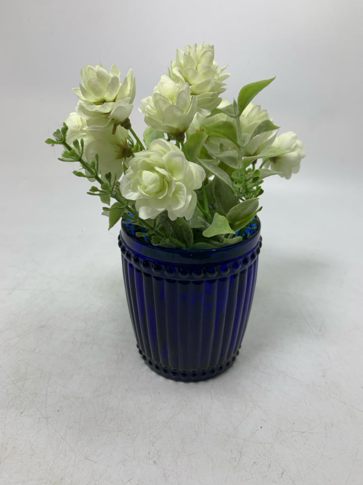 DARK BLUE GLASS VASE W/ SMALL WHITE FLOWERS.