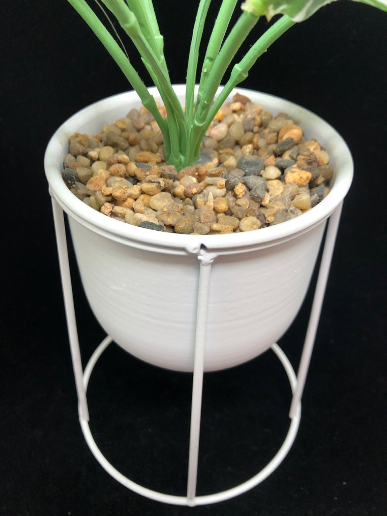 FAUX GREEN PLANT IN WHITE RAISED METAL PLANTER.