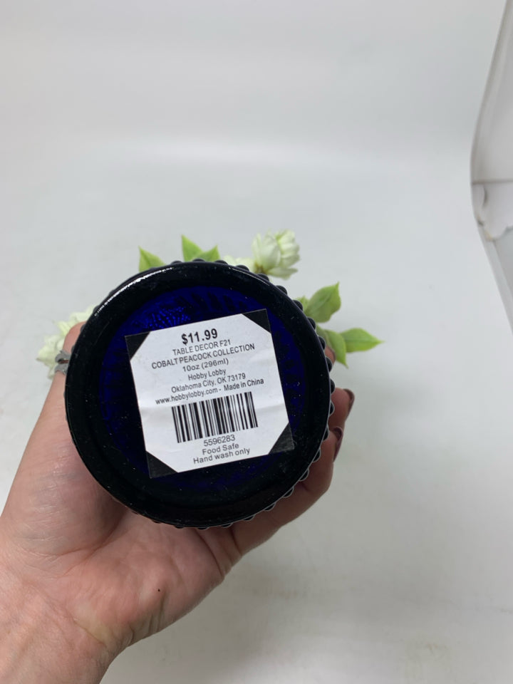 DARK BLUE GLASS VASE W/ SMALL WHITE FLOWERS.
