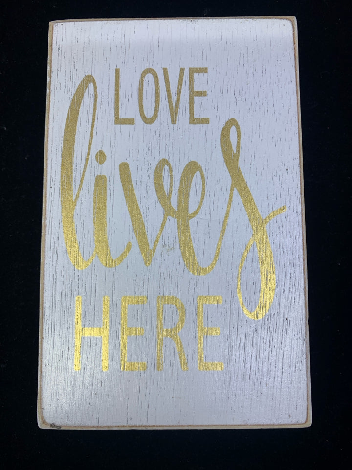 LOVE LIVES HERE WHITE AND GOLD SIGN.