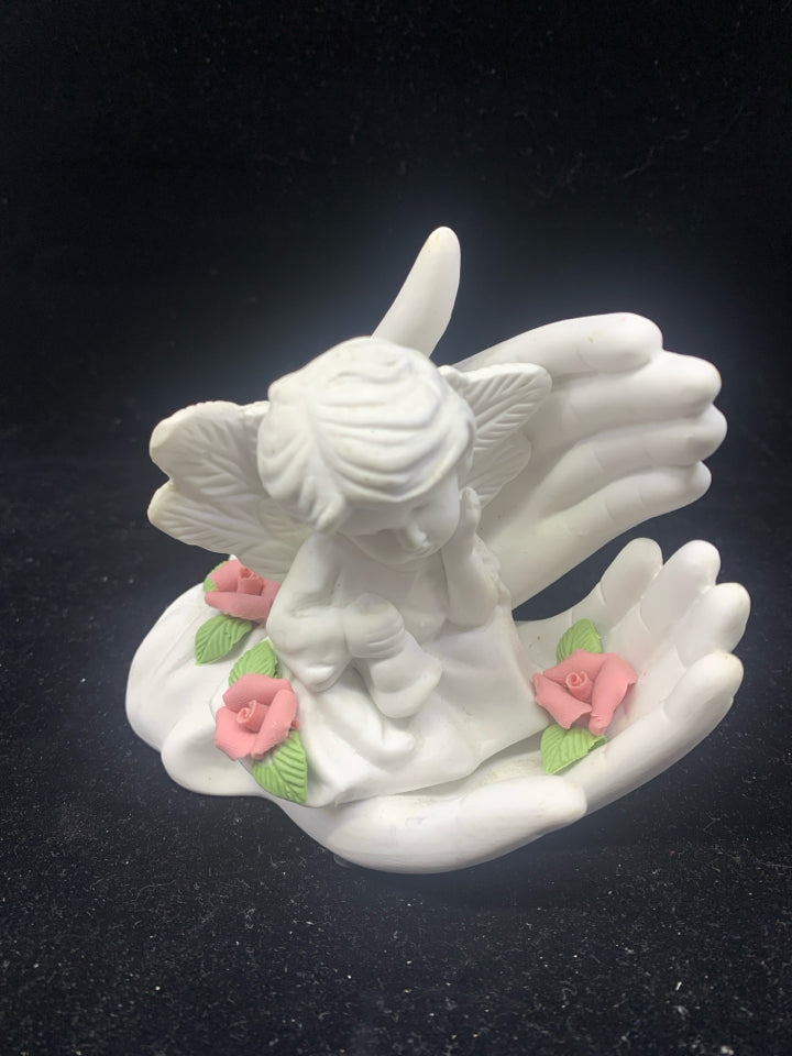 WHITE HANDS HOLDING CHERUB FIGURINE.