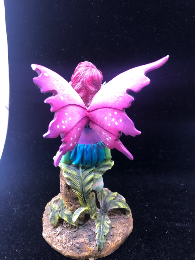 RESIN FAIRY SITTING ON A STUMP W/ PURPLE WINGS.