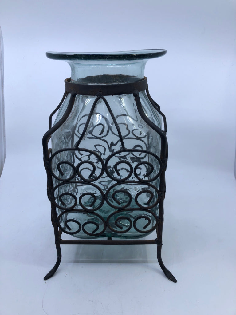 THICK GLASS VASE ENCASED IN SCROLL METAL FOOTED CAGE.