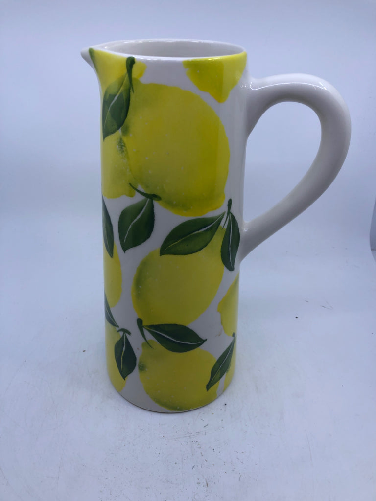 TALL WHITE CERAMIC PITCHER WITH LEMONS.