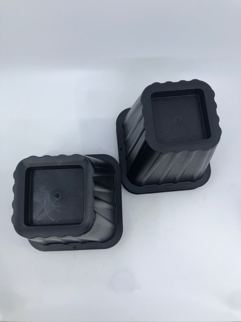 4 BLACK PLASTIC BED RISERS.