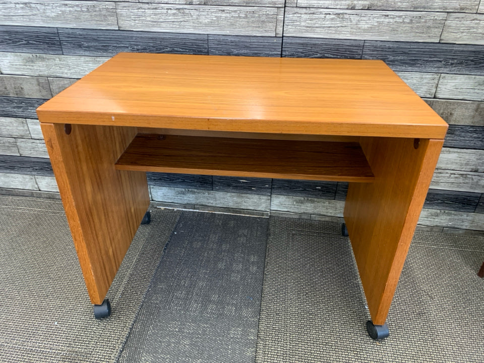 SMALL HEAVY WOOD DESK ON WHEELS W/ INSIDE SHELF.