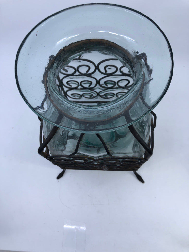 THICK GLASS VASE ENCASED IN SCROLL METAL FOOTED CAGE.