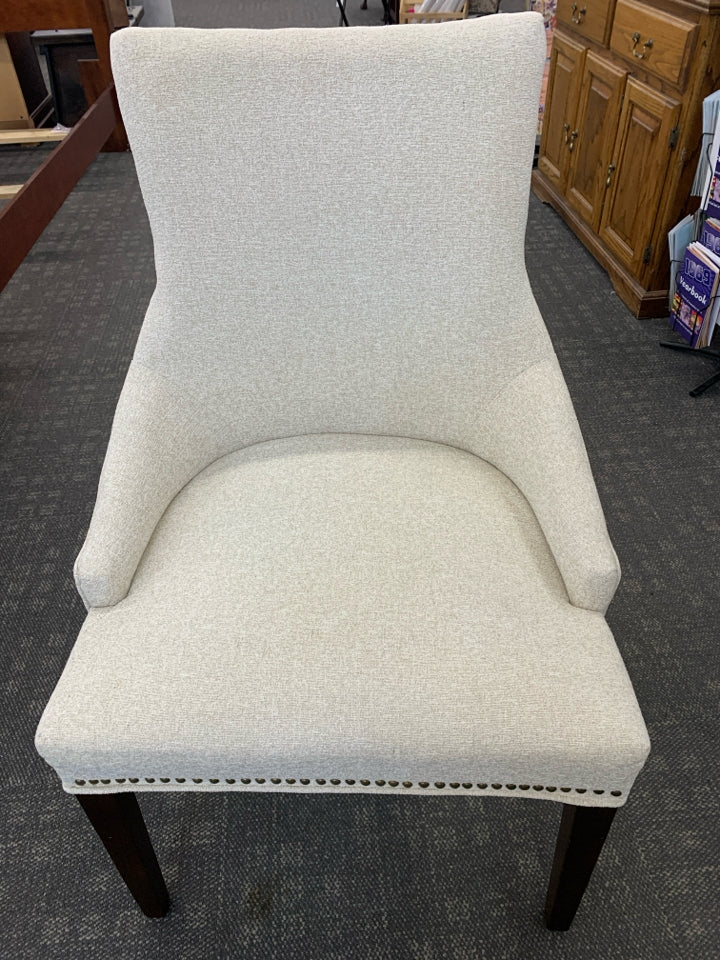 UPHOLSTERED CREAM CHAIR W/DARK WOODEN LEGS.