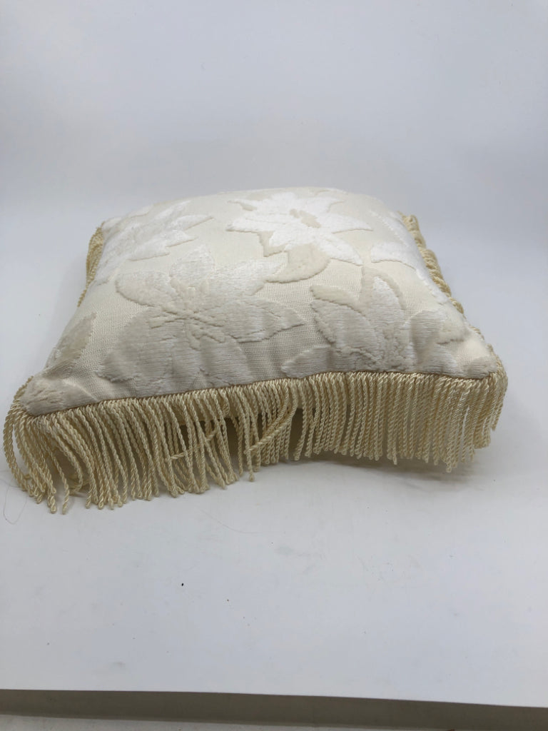 WHITE SMALL PILLOW W/ EMBOSSED FLOWERS FRINGE ON EDGES.