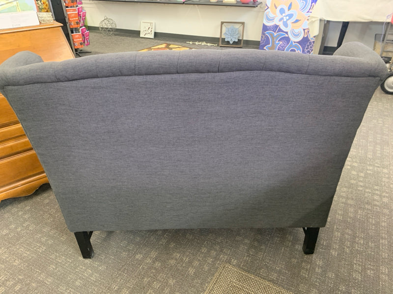 DARK GRAY WING BACK TUFTED LOVE SEAT WITH NAIL HEAD DETAILS.